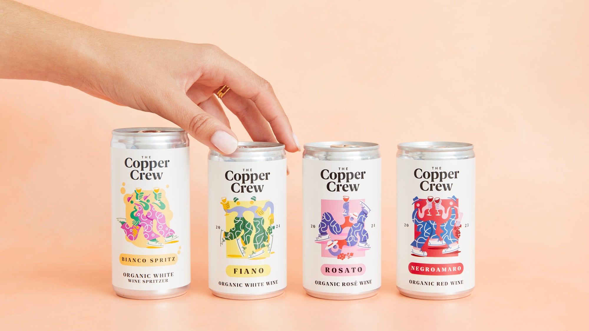 Four cans of Copper Crew wine with colorful labels on a beige background.
